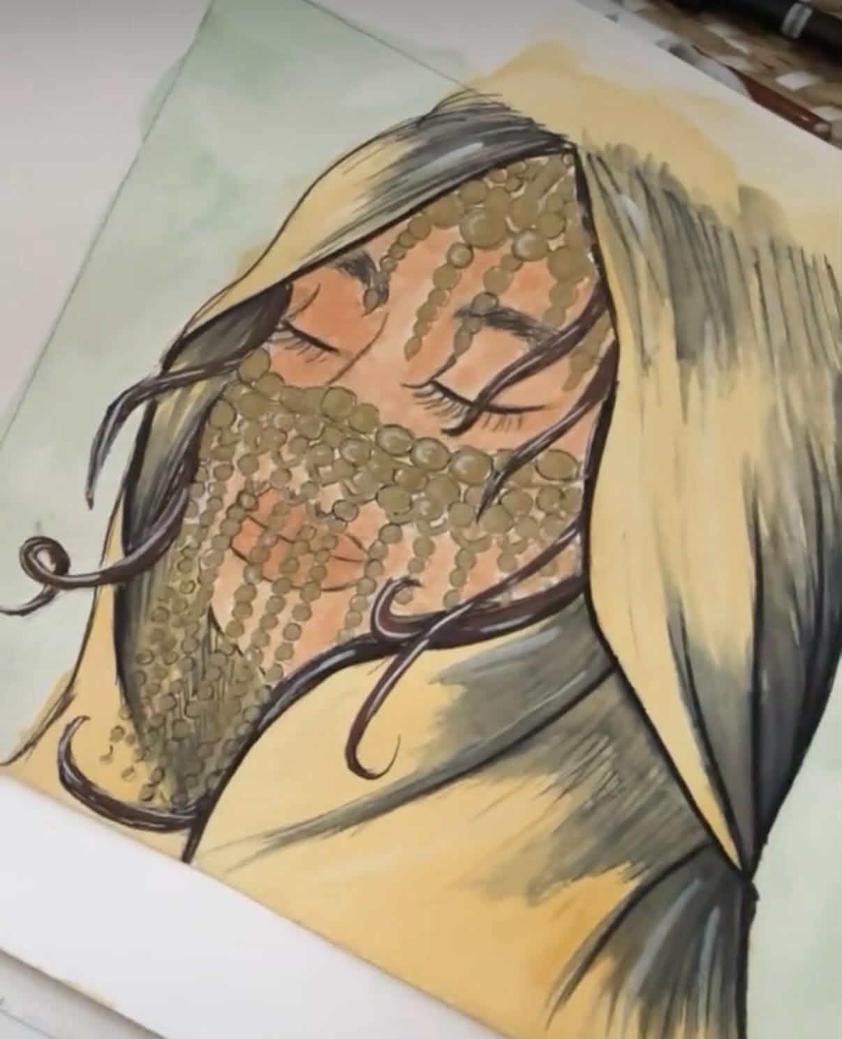 Aquarelle sur la table de l'atelier : le visage d'une femme aux yeux clos, voilé de rangs de perles dorées, les cheveux au vent